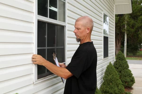 A storm damage insurance claims inspector inspecting a window after it’s been damaged by a storm.