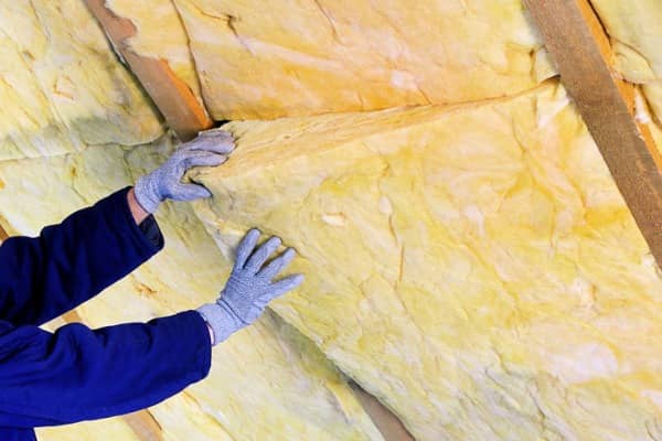 Person applying insulation to roof to stop ice dams