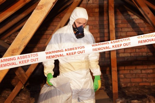 A worker in a safety suit removing materials covered in asbestos.