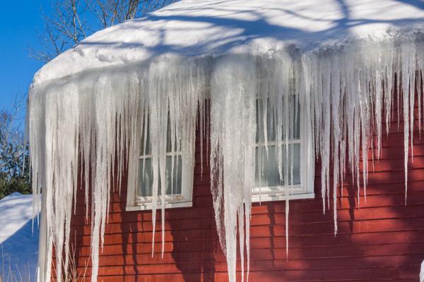An ice dam forms on a red house.