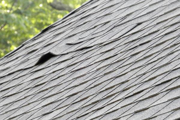A damaged shingle along the side of a roof