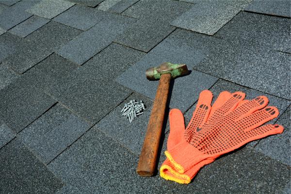 Gloves and nails rest on some shingles